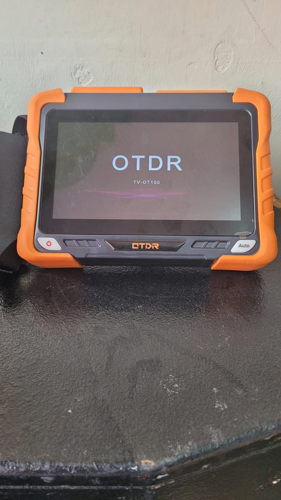 Rugged orange OTDR test unit starting up on a field work surface